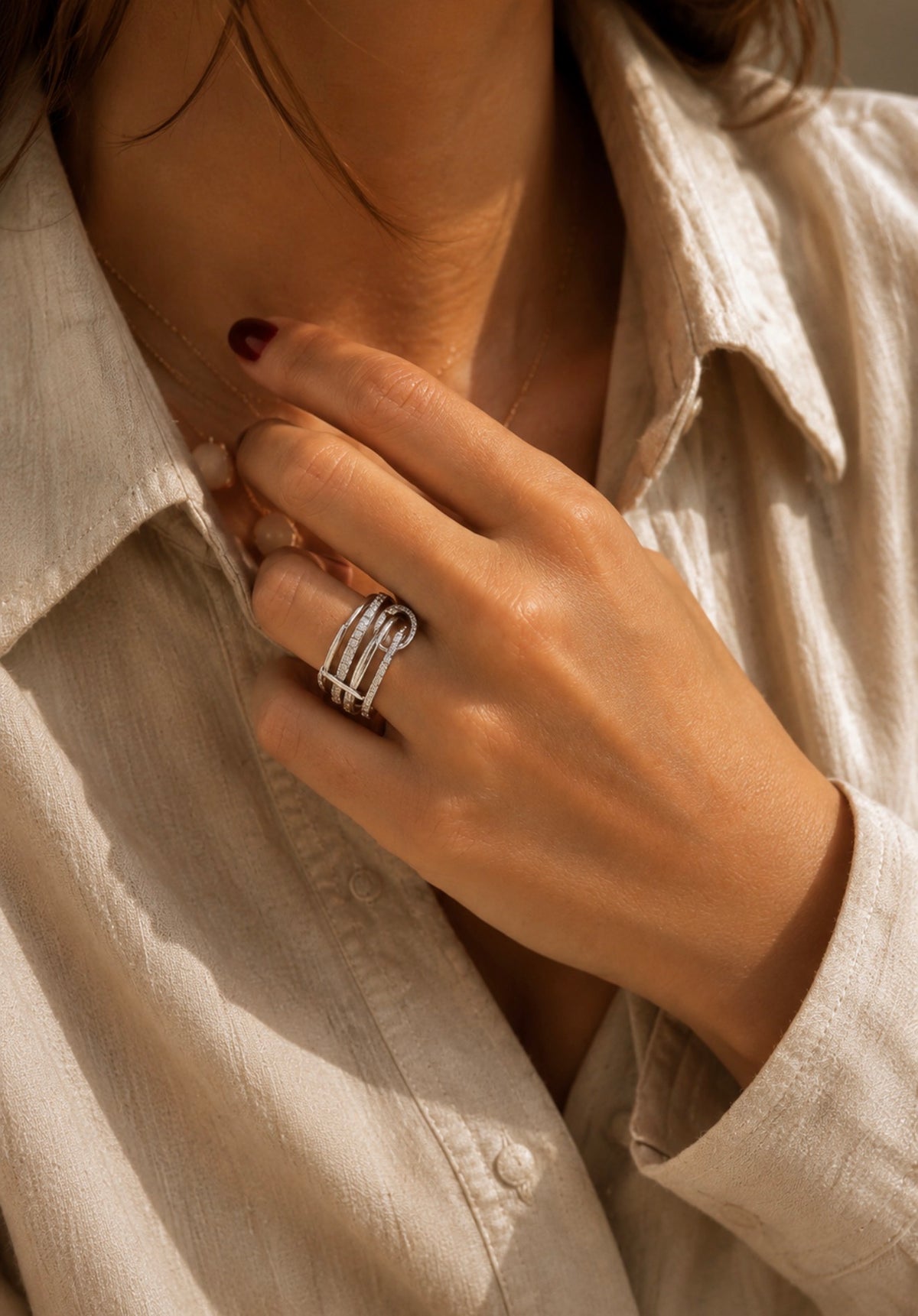 Bague Sienna argentée au design large portée au doigt d'une femme avec une chemise claire