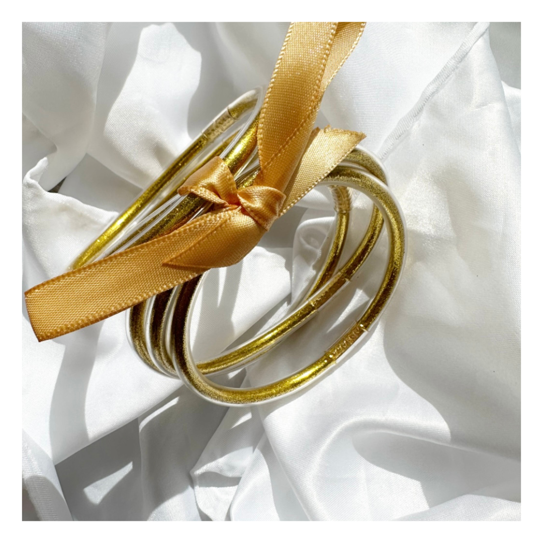 Gros plan sur plusieurs bracelets joncs bouddhistes dorés Lucie avec ruban jaune