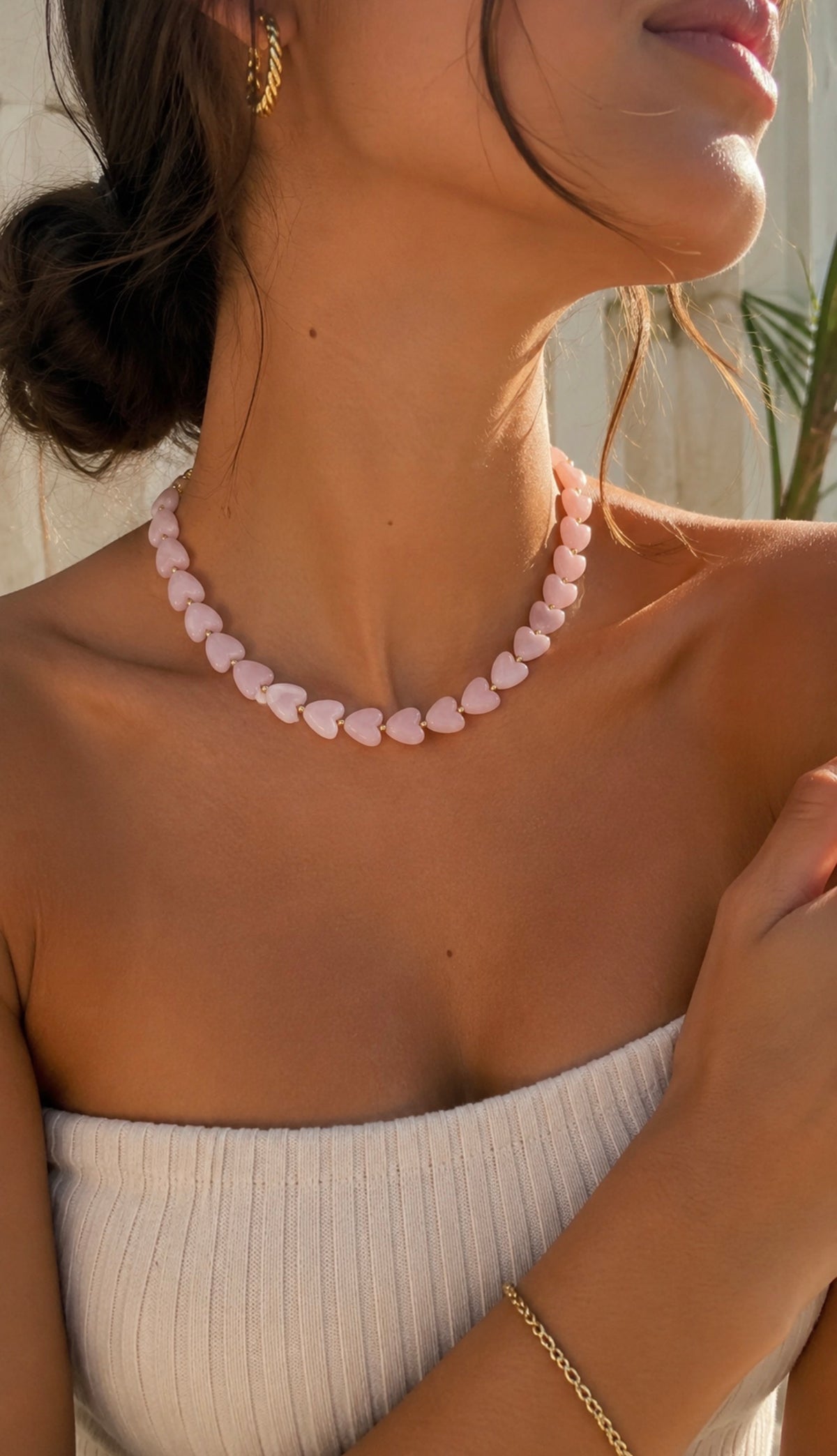 Collier Ama rose pastel composé de perles en forme de cœur, porté par une femme avec un bustier blanc. Bijou fantaisie coloré LAU.THENTIK.