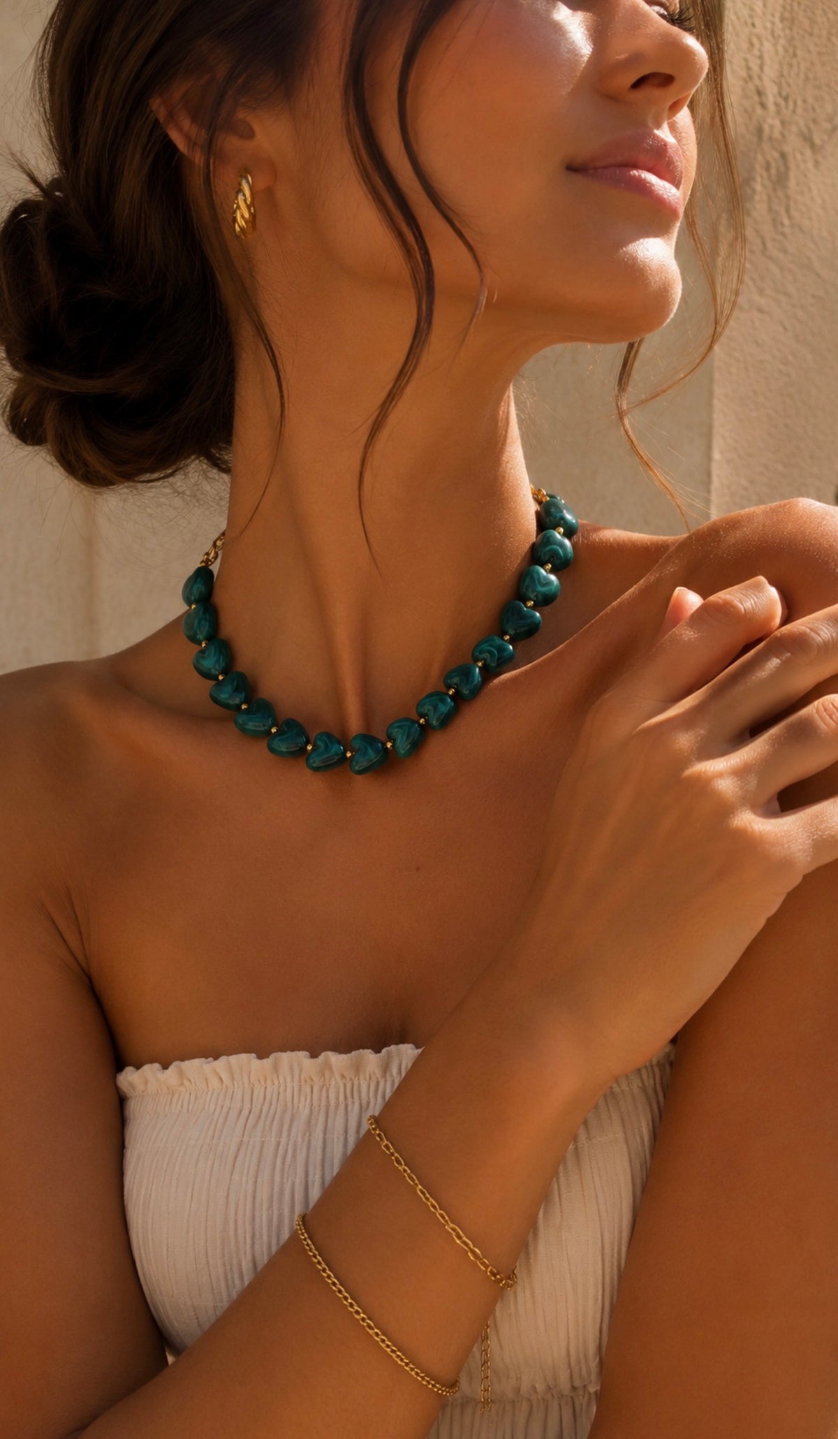 Collier Ama vert turquoise en perles en forme de cœur porté par une femme avec un bustier blanc. Bijou fantaisie coloré signé LAU.THENTIK.