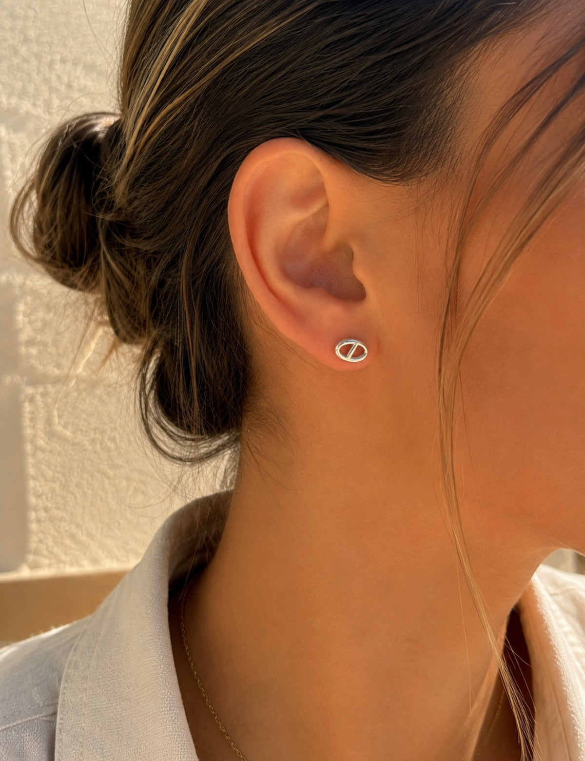 Boucle d'oreille Leonie argentée en acier inoxydable, motif maille marine, portée à l'oreille d'une femme