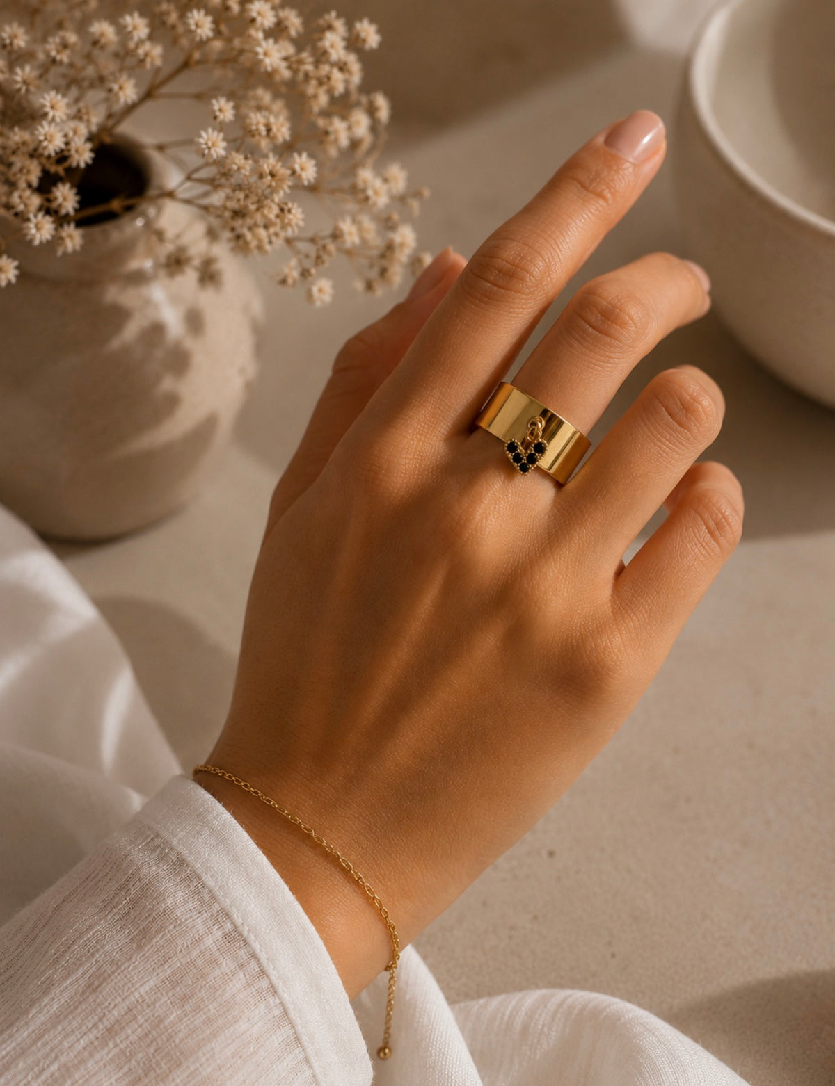 Bague Mathilde dorée en acier inoxydable portée au doigt d'une femme près d'une tasse blanche