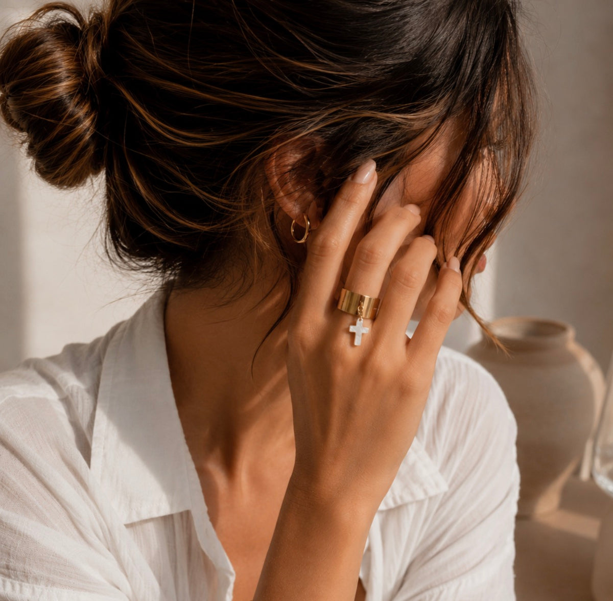 Bague Sophie en acier inoxydable avec petite breloque, portée au doigt d'une femme en chemise blanche