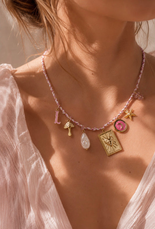 Collier Emy à cordon rose avec charms et pendentifs colorés, porté par une femme en blouse blanche